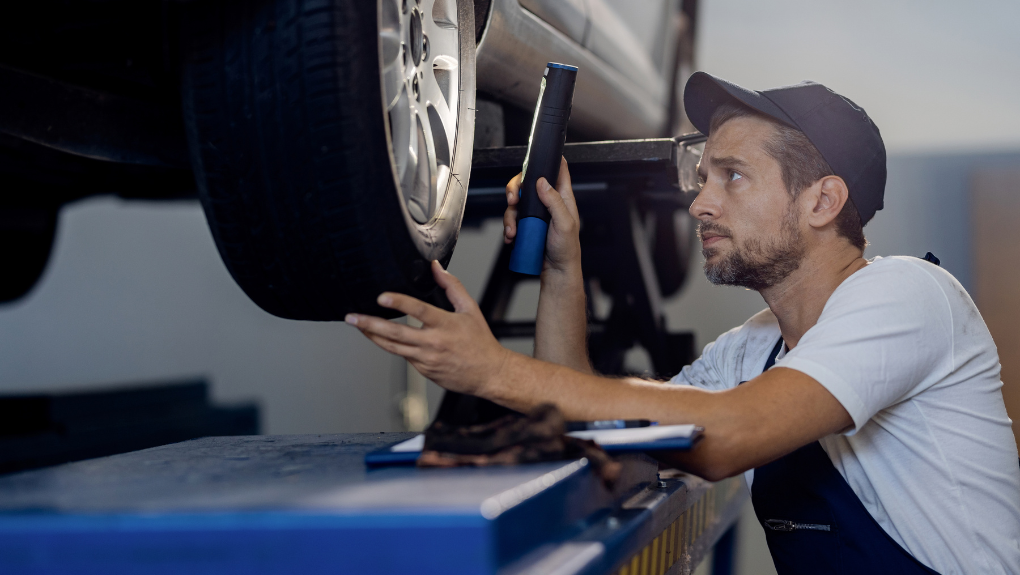 Technician measuring brake pad thickness during a pre-purchase vehicle inspection at EDP Automotive in Victoria, BC